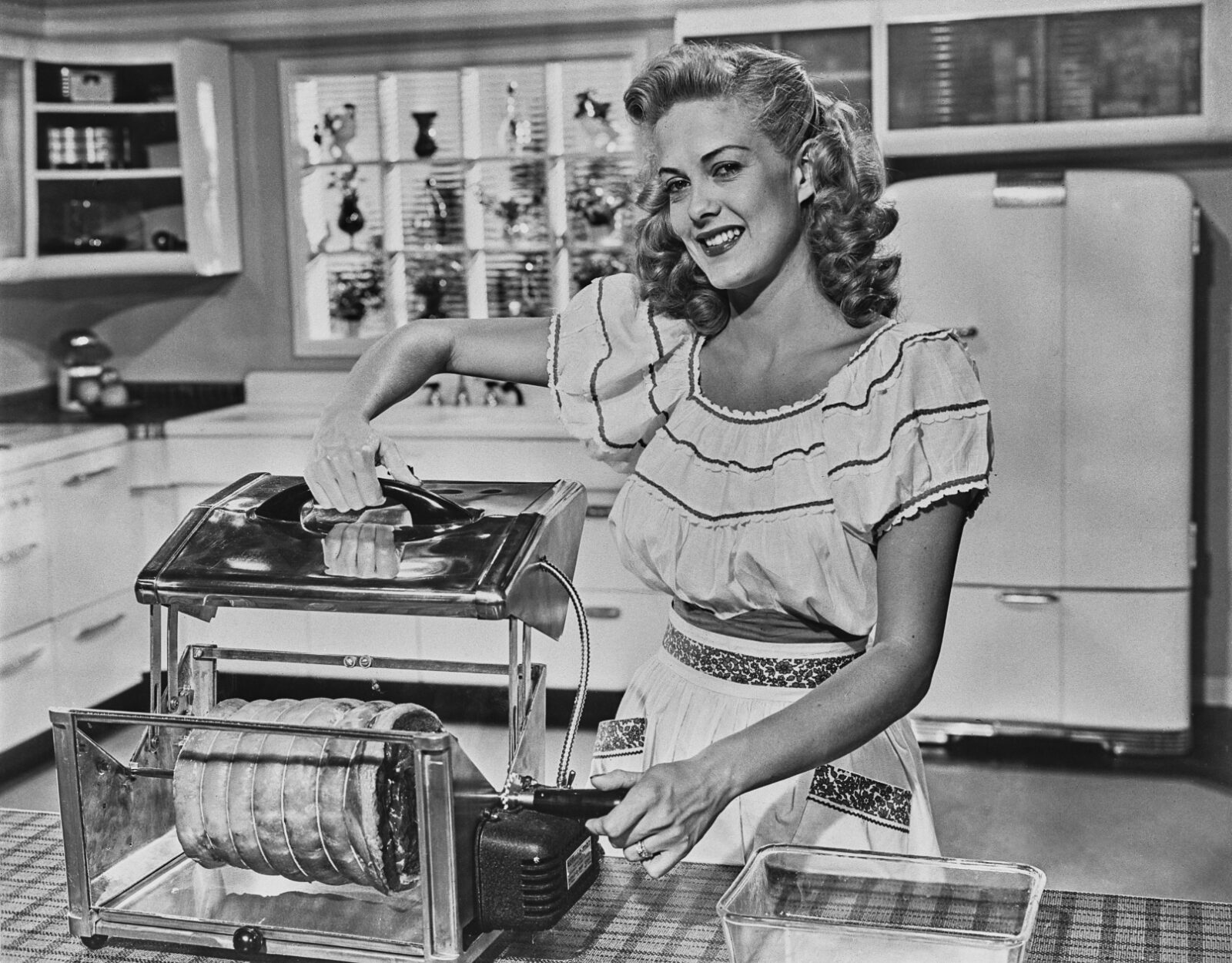 Black and white image of a 50s housewife in a kitchen smiling