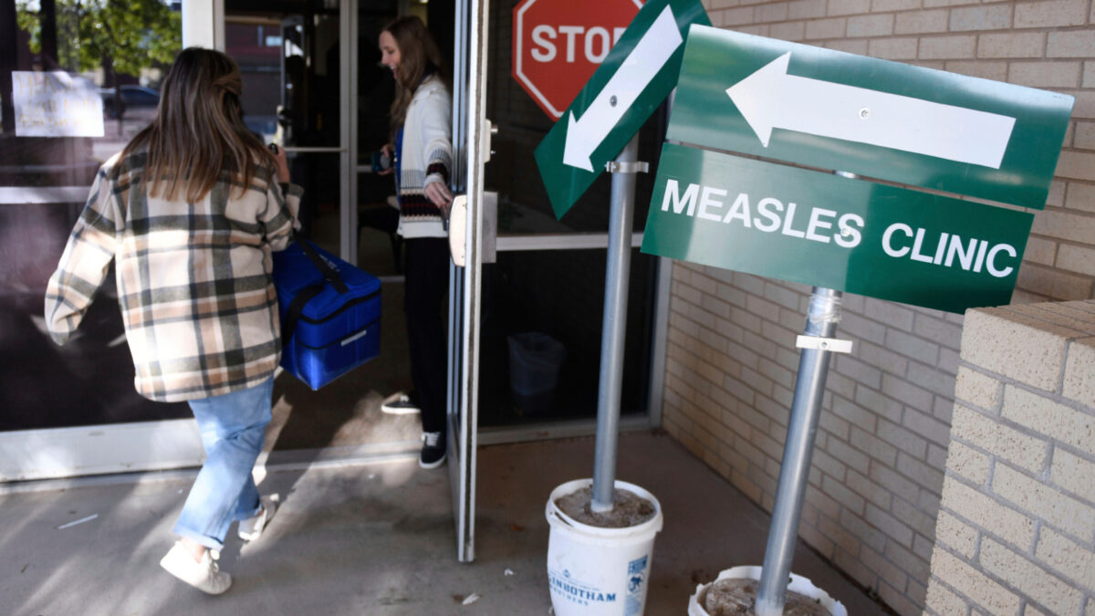 Health department staff members enter the Andrews County Health Department measles clinic carrying doses of the measles, mumps and rubella vaccine, April 8, 2025 in Andrews, Texas.